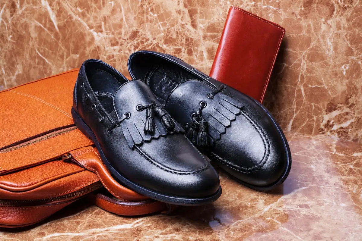 Black leather tassel loafers with fringe detailing and a classic round toe design.