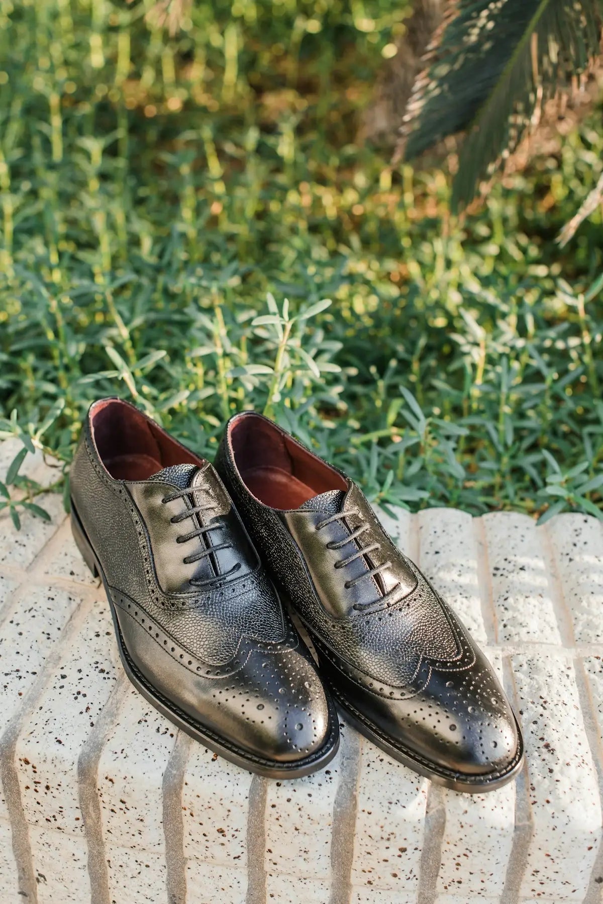 Classic black leather wingtip oxford shoes with a subtle distressed texture and red lining.