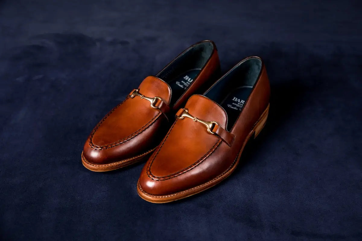 Brown leather loafer with horsebit detail and tan accent.