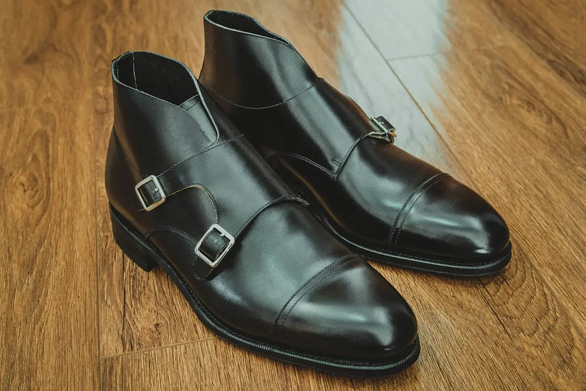 Black leather double monk strap ankle boots with silver buckles.