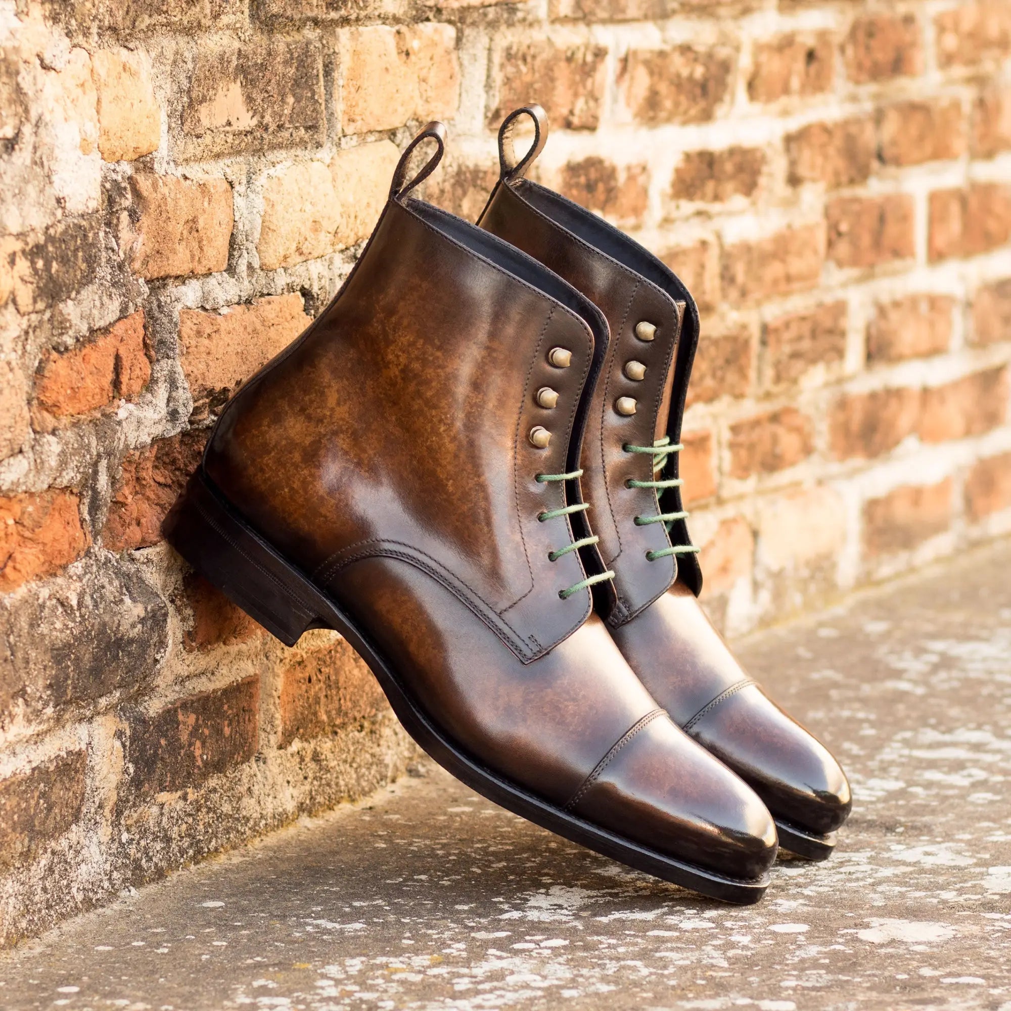 Brown leather lace-up ankle boots with cap-toe design and studded details.