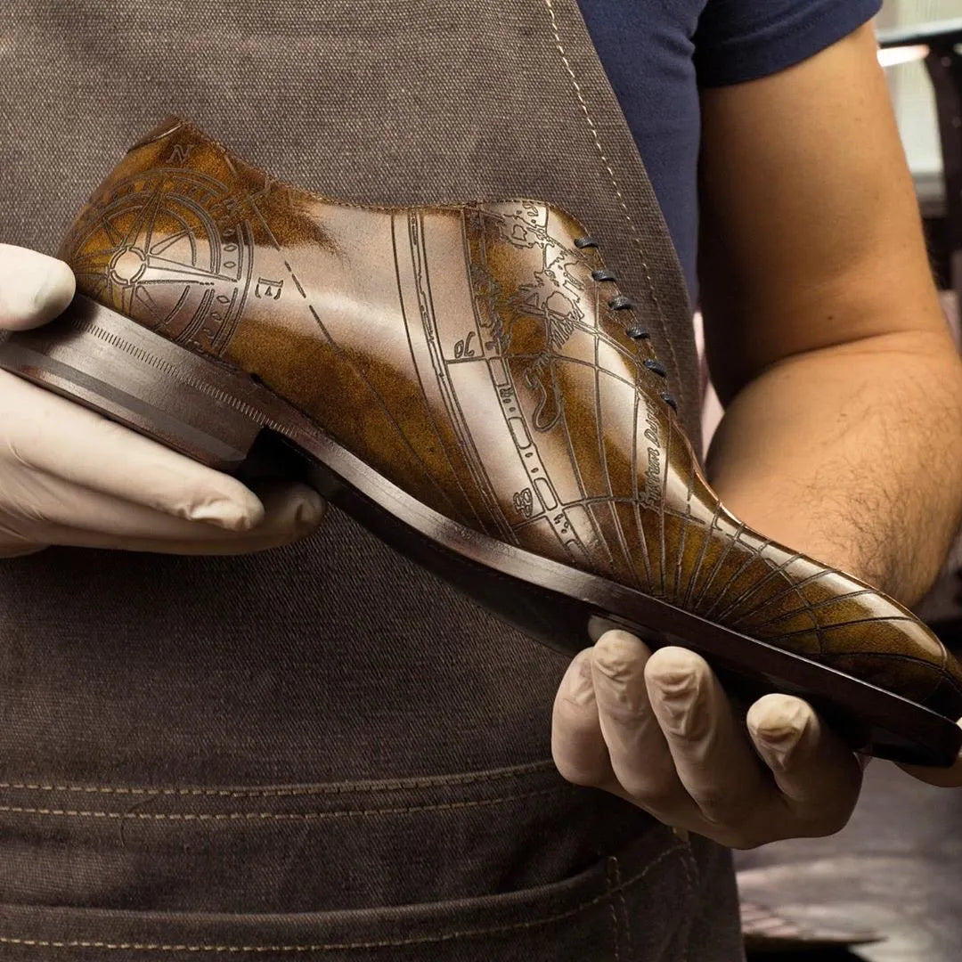 Gold and brown leather dress shoe with intricate embossed design featuring a ship motif.
